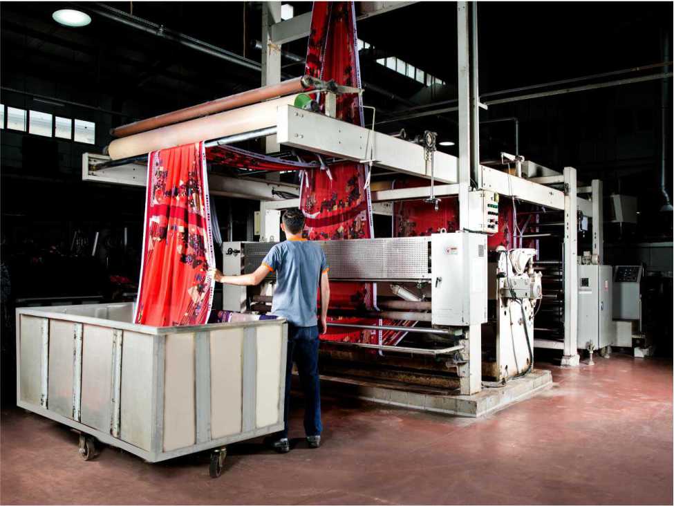 a fabrics dyeing machine in a fabrics industry which is operated by a man wearing a blue shirt and black pent