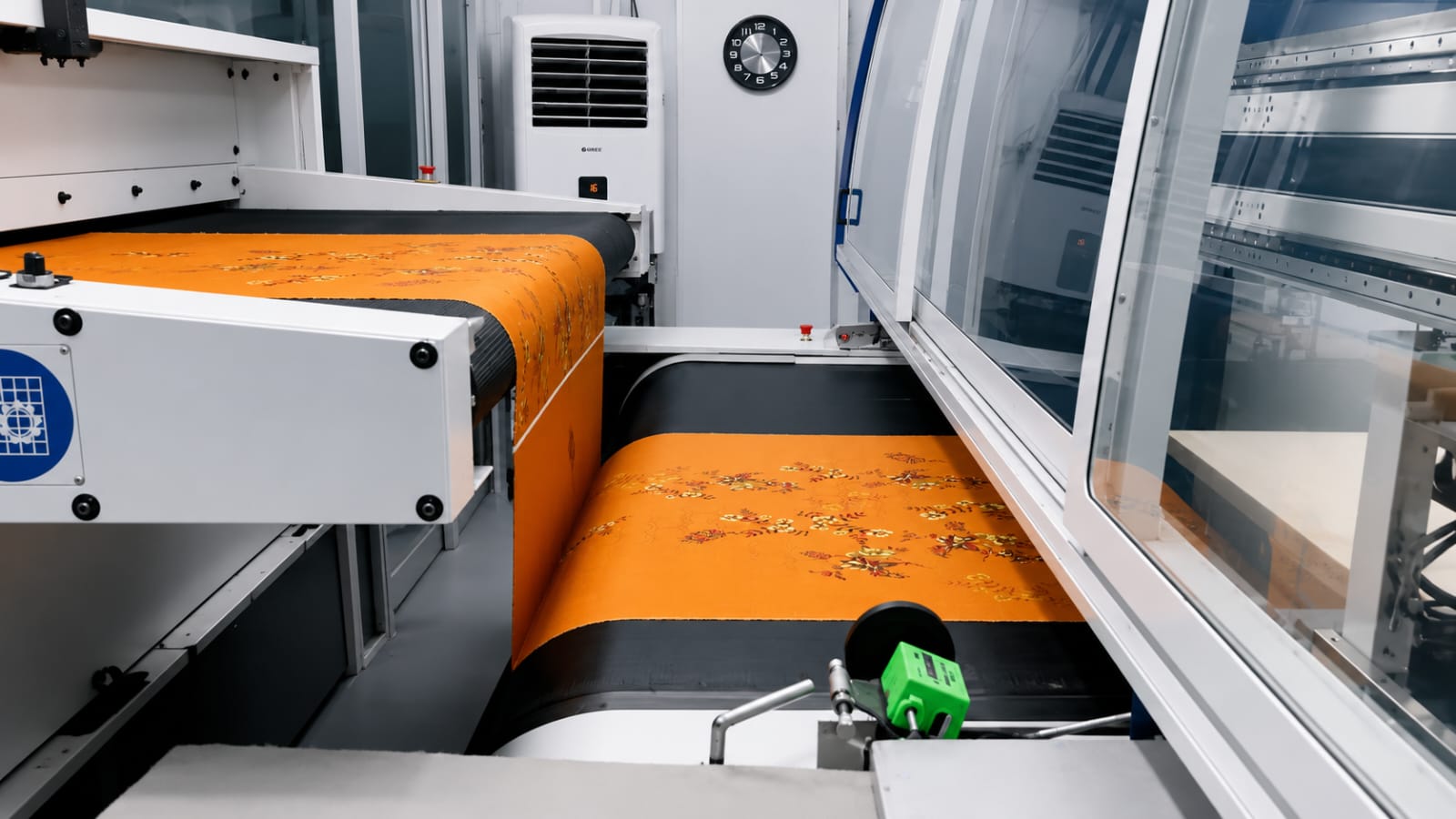 a orange cloth been printed in a digital printer in a textile mill background will the printing room